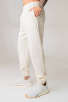 A man wearing the Vitality Uni Cozy Jogger in Oat