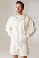 A man wearing the Vitality Uni Cozy Zip in Oat