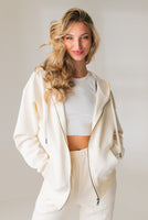 A woman wearing the Vitality Uni Cozy Zip in Oat