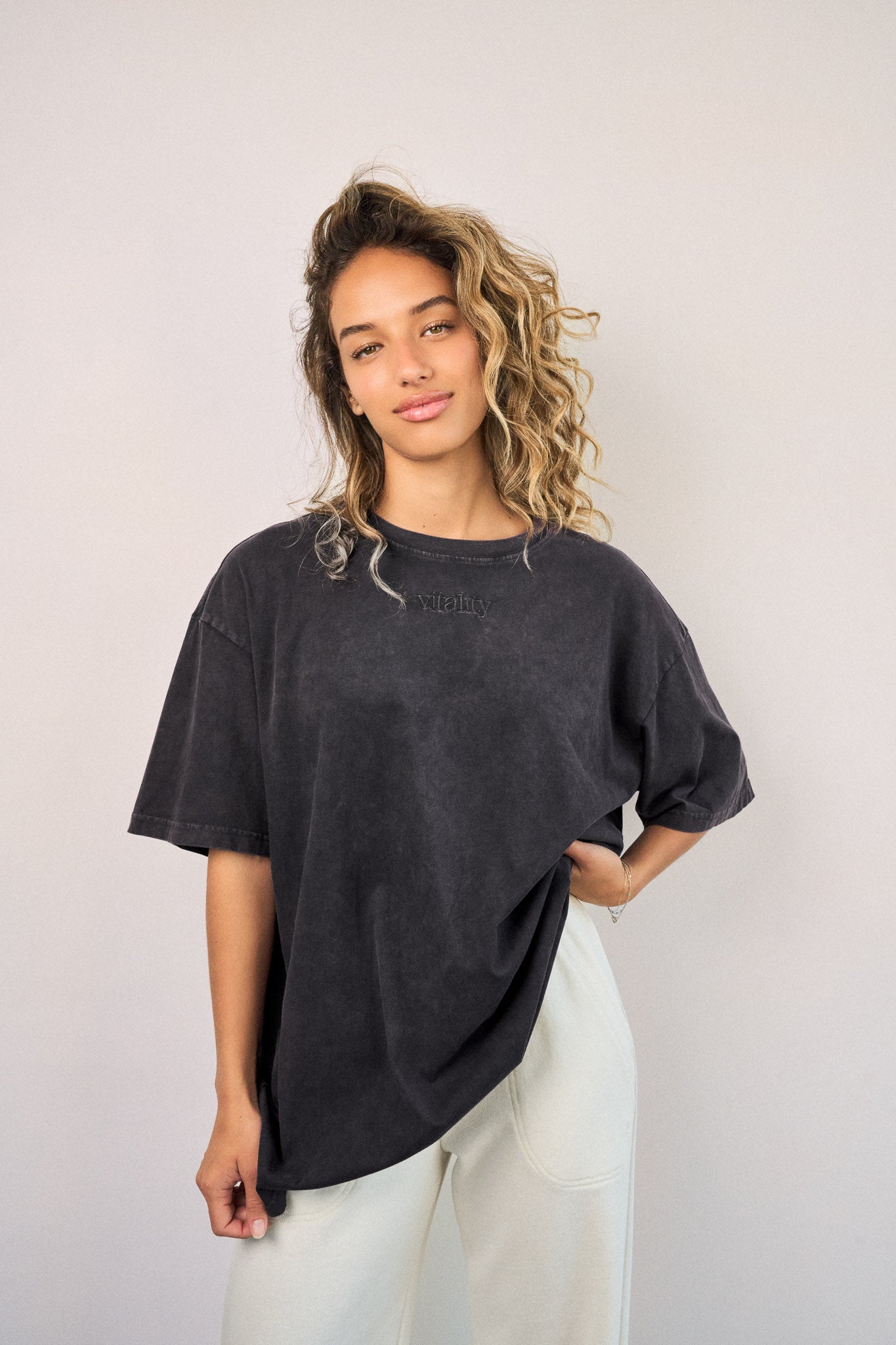 A woman wearing the Vitality Retro Uni Tee - Iron Washed