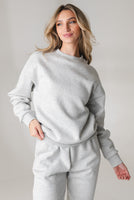A woman wearing the Vitality Uni Cozy Crew - Stone Marl