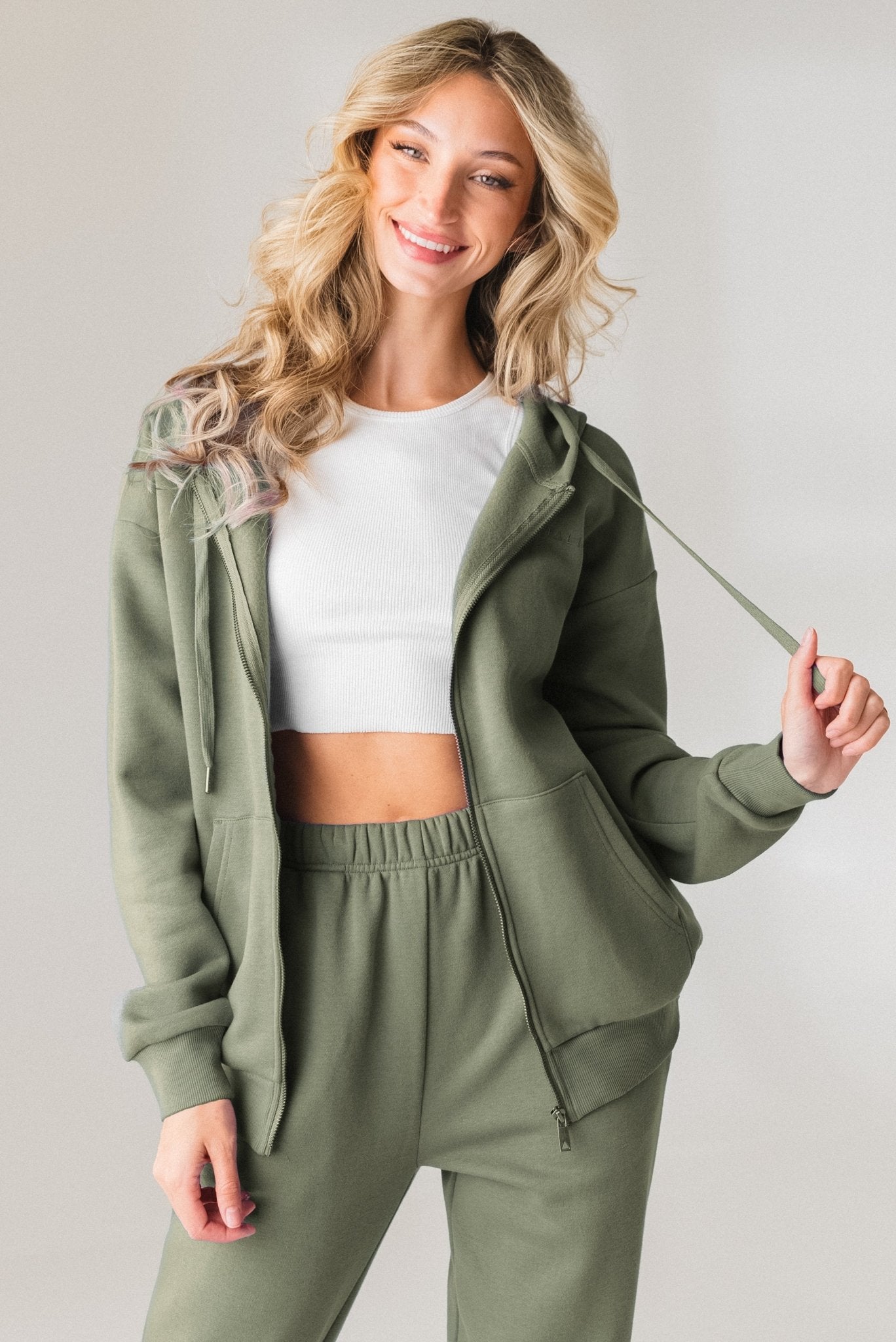A woman wearing the Vitality Uni Cozy Zip in Willow
