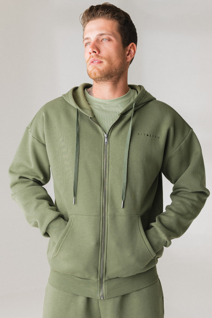 A man wearing the Vitality Uni Cozy Zip in Willow