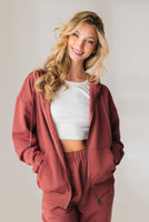 A woman wearing the Vitality Uni Cozy Zip in Rosewood