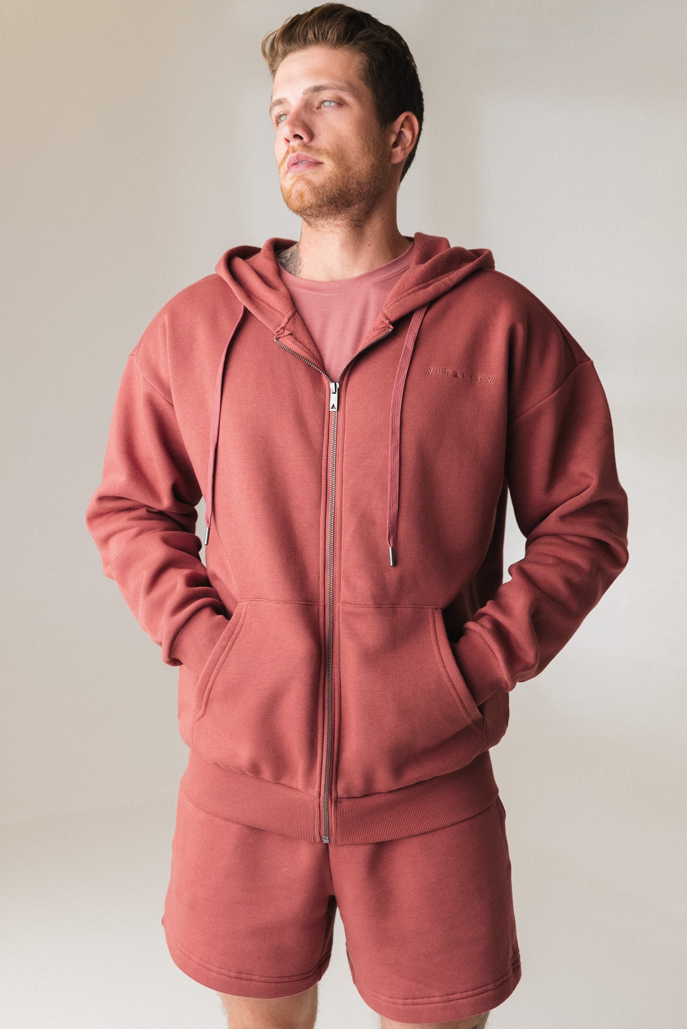 A man wearing the Vitality Uni Cozy Zip in Rosewood