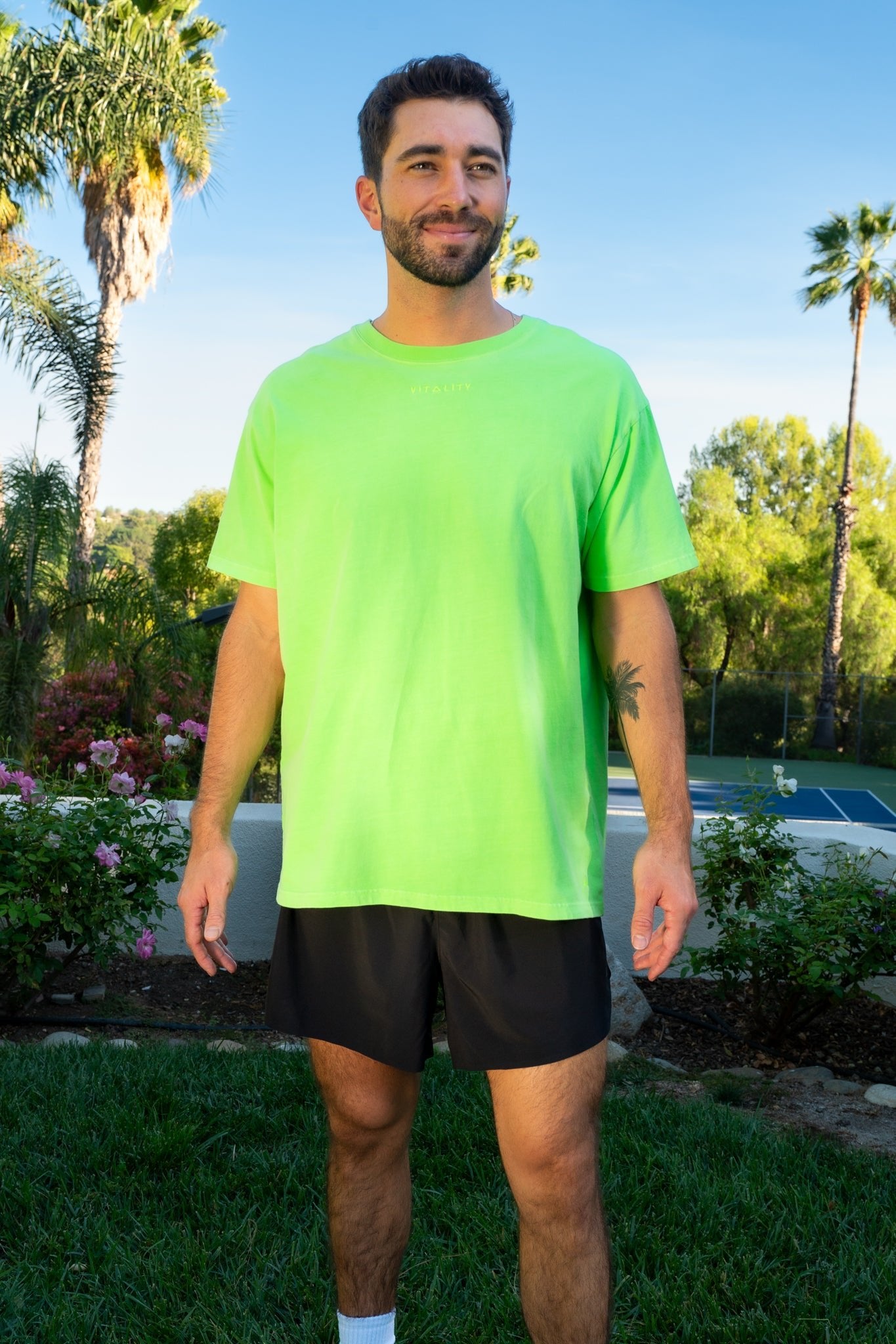 A man wearing the Vitality Retro Uni Tee - Neon Green