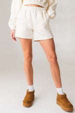 A woman wearing the Vitality Uni Cozy Short in Oat